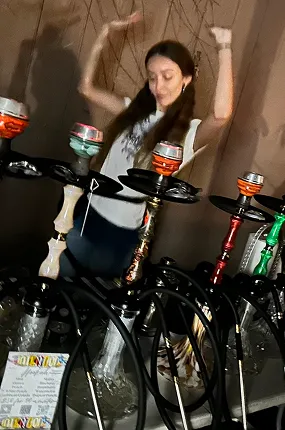 Guest dancing at a house party next to a row of colorful rental hookahs in New York