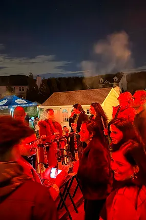 Smiling guests chatting at an outdoor evening event with a hookah station and smoke in the background